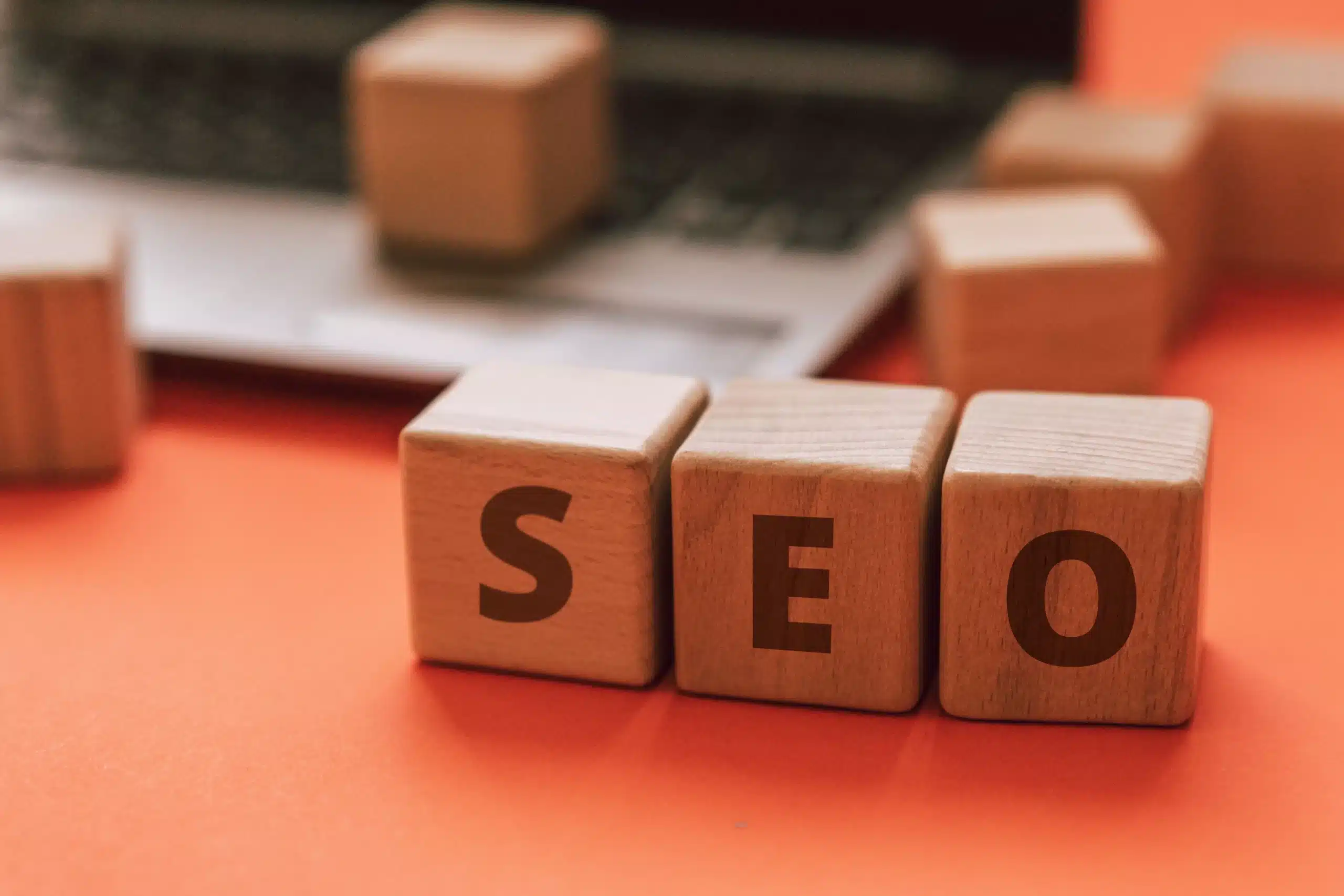 Three wooden blocks with letters 'SEO' arranged on top, symbolizing search engine optimization.